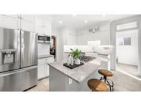 Bright, all-white kitchen with stainless steel appliances and a marble-topped island with bar stool seating at 2823 N Lafayette St, Denver, CO 80205