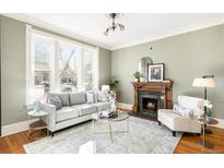 Bright living room with fireplace, light gray sofa, and large windows offering natural light at 2823 N Lafayette St, Denver, CO 80205