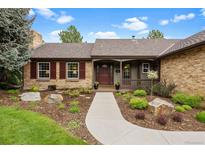 Charming single-story brick home featuring a landscaped front yard with beautiful trees and a walkway to the front door at 7881 S Ivy Ct, Centennial, CO 80112