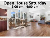 Bright living room with open floor plan, fireplace, hardwood floors, kitchen bar, and plenty of natural light at 1204 S Balsam Ct, Lakewood, CO 80232