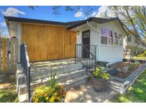 Charming home featuring a modern design, landscaped front yard, and inviting entrance with flower pots at 3469 Benton St, Wheat Ridge, CO 80212