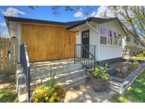 Inviting home featuring wood paneling, black trim, front porch and freshly landscaped front yard at 3469 Benton St, Wheat Ridge, CO 80212