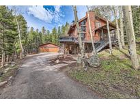 Beautiful two-story home with a large deck and an attached two-car garage, nestled among trees at 266 Lodgepole Dr, Evergreen, CO 80439
