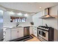 Updated kitchen featuring stainless steel appliances, stylish backsplash, and white cabinetry at 3500 W 55Th Ave, Denver, CO 80221