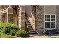 Attractive apartment exterior featuring stone accents, well-manicured bushes, and stairs to the upper level at 4054 S Carson St # 102, Aurora, CO 80014