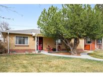 Charming brick home featuring a well-maintained lawn, mature tree and inviting front porch with red chairs at 2211 Lamar St, Edgewater, CO 80214