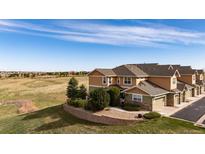 Inviting townhome exterior with neutral siding, mature landscaping, and a retaining wall, set against an expansive field at 3661 S Perth Cir # 6-101, Aurora, CO 80013