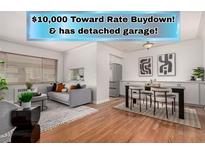Bright living room with hardwood floors, a gray sofa, and access to dining area with stainless steel appliances at 1454 Jersey St # 104, Denver, CO 80220