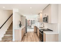 Modern kitchen with stainless steel appliances, light wood floors, and bright white countertops offers a sleek design at 115 W 2Nd Ave # 101, Denver, CO 80223