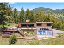 Stunning mountain home featuring a deck, hot tub, and lush landscaping at 187 Marion Dr, Evergreen, CO 80439