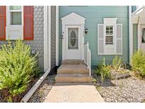 Charming front door with decorative window and light fixture, nestled amongst manicured landscaping at 10567 Dartmouth, Lakewood, CO 80227