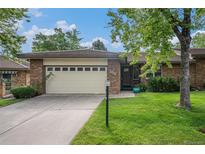 Charming brick home featuring a well-maintained lawn, mature tree, and attached two-car garage at 8022 W 78Th Way, Arvada, CO 80005