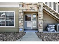 Inviting condo front door with stone detail, an ADT security system and an exterior stairway at 9963 E Carolina Cir # 104, Aurora, CO 80247
