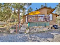 Charming exterior featuring a deck with a yellow umbrella, stone accents, and lovely landscaping at 11798 Ridge Rd, Golden, CO 80403