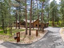 Charming home featuring a long driveway, complemented by mature trees and lush landscaping at 5846 S Pike Dr, Larkspur, CO 80118