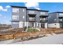 Modern townhome with a gray exterior, small balconies, and a charming front yard with a wooden fence at 2127 Alcott Way, Broomfield, CO 80023