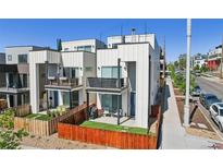 Modern home exterior featuring white siding, balconies, fenced yard and street view at 1299 Newton St, Denver, CO 80204