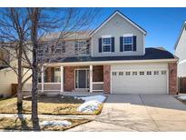 Charming two-story home featuring a brick facade, a covered porch, and an attached two-car garage at 6232 W Cross Dr, Littleton, CO 80123