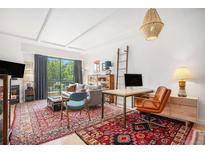 Bright living room features large window, hardwood floors, and a stylish workspace nook with a leather chair at 180 Cook St # 406, Denver, CO 80206