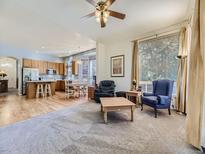 Bright open-concept living space with hardwood floors and breakfast bar flowing into the kitchen and dining area at 17284 E Hawksbead Dr, Parker, CO 80134