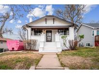 Charming home with white exterior, gray trim, landscaped yard and front yard sidewalk leading to the entrance at 2933 Benton St, Wheat Ridge, CO 80214