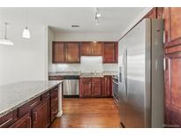 Modern kitchen featuring stainless steel appliances, granite countertops, and dark wood cabinetry at 13598 Via Varra # 105, Broomfield, CO 80020