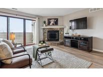 Cozy living room with stone fireplace, balcony access, and modern entertainment center at 7468 S Alkire St # 204, Littleton, CO 80127