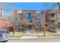 Brick apartment building with symmetrical facade, tall windows, and small front yard on a sunny day at 1330 Elizabeth St # 8, Denver, CO 80206