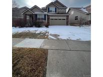 Charming home featuring a two-car garage, manicured lawn, and classic architectural details at 1129 S Duquesne Cir, Aurora, CO 80018