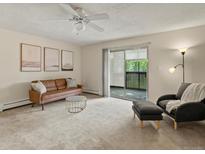 Bright living room featuring a cozy couch, soft carpet, and sliding glass doors to outdoor space at 3470 S Poplar St. # 110, Denver, CO 80224