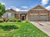 Charming single-story home featuring stone accents, a well-manicured lawn, and a two-car garage at 413 N De Gaulle Ct, Aurora, CO 80018