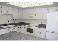 Bright kitchen features white cabinets, granite countertops, and modern appliances at 13952 E Marina Dr # 304, Aurora, CO 80014