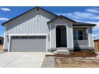 Charming single-Gathering home with a grey exterior, attached garage, and a cozy front porch with white railings at 1613 Bloom St, Brighton, CO 80601