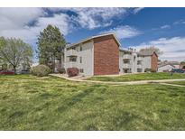 A well-maintained apartment building with brick accents and multiple balconies is surrounded by lush green grass at 10150 E Virginia Ave # 301, Denver, CO 80247