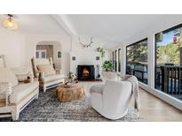 Bright living room featuring a fireplace, hardwood floors, and large windows with outdoor views at 7869 S Turkey Creek Rd, Morrison, CO 80465