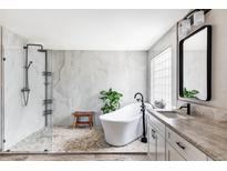 Bright bathroom with white freestanding tub, glass shower, and neutral tile at 1280 Galactic Pl, Castle Rock, CO 80108