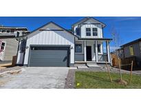 Charming two-story home with a modern farmhouse design, featuring a gray garage door and well-manicured lawn at 6071 Caribou Dr, Brighton, CO 80601