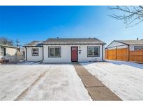 Charming single story home with a red door and snow covered yard at 1708 Oswego St, Aurora, CO 80010