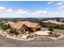 Beautiful exterior elevation with a red-tiled roof, stucco siding and a circular driveway providing stunning mountain views at 6170 Falcon Ln, Morrison, CO 80465