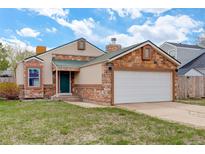Charming single-Gathering home with brick accents, a green front door, and a two-car garage at 11420 E 1St Ave, Aurora, CO 80010