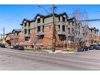 Brick apartment building featuring multi-level balconies on a corner lot with metered street parking and bare trees under a clear blue sky at 2901 Wyandot St # 18, Denver, CO 80211