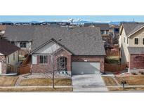 Charming single-Gathering home featuring a well-maintained lawn, brick facade, and attached two-car garage at 5280 Longs Peak St, Brighton, CO 80601