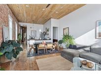 Spacious living room features hardwood floors, brick walls, wood ceiling, and large windows at 701 W 6Th Ave, Denver, CO 80204