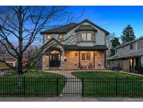 Charming two-story home featuring a stone facade, arched entryway, covered porch, and landscaped front yard at 2500 S Clayton St, Denver, CO 80210