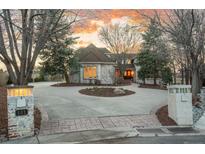 Elegant home with a circular driveway, manicured landscaping, and brick accents creating a welcoming curb appeal at 101 Glenmoor Ln, Cherry Hills Village, CO 80113
