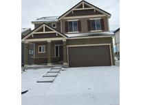 Two-story home featuring a covered porch, two-car garage, and steps leading to the front door, with snow covering the yard at 4995 S Algonquian Way, Aurora, CO 80016