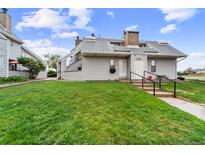 Charming townhome with manicured lawn, gray siding, and inviting entrance steps at 17004 E Tennessee Dr # 103, Aurora, CO 80017