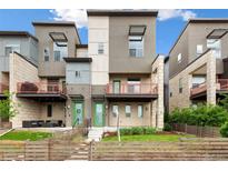 Modern townhome with a well-kept lawn, a wood fence, and a lovely entrance and porch with red railings at 5668 Galena St, Denver, CO 80238