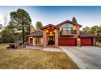 Charming brick home featuring a three-car garage, balcony, and a welcoming front yard with a fire pit at 11437 Tomichi Dr, Franktown, CO 80116