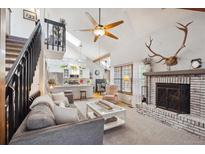 Open-concept living area with fireplace and views of the kitchen and upper level at 8010 Holland Ct # D, Arvada, CO 80005